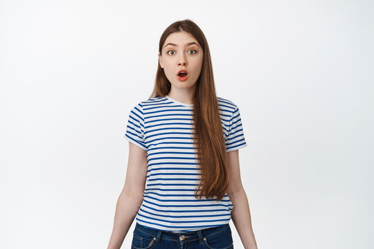 Image of surprised girl drop jaw, say wow and stare in awe at camera, standing impressed against white background