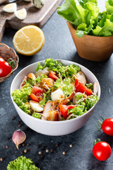 Caesar Salad with smoked chicken and parmesan on a plate on dark background. Top view