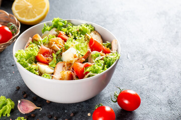 Caesar Salad with smoked chicken and parmesan on dark background. Copy space.