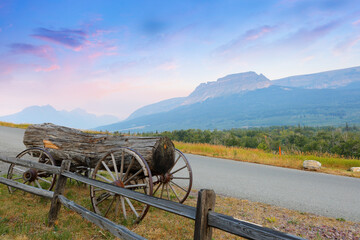 Fototapeta na wymiar Montana Landscape with an old wagon and a wood log at sunrise in West Glacier, Montana USA