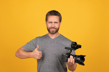 cheerful bearded man videographer making movie for vlog with camcorder showing thumb up, filming