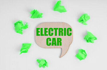 On a white background, there are crumpled green pieces of paper and a wooden sign with the inscription - Electric Car