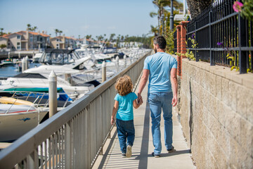 Fototapeta premium parent with small child boy. dad with kid on summer day. parenting and fatherhood. back view.