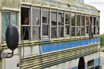 Dilapidated and rusty bus with broken windows in a remote area. Scrap.