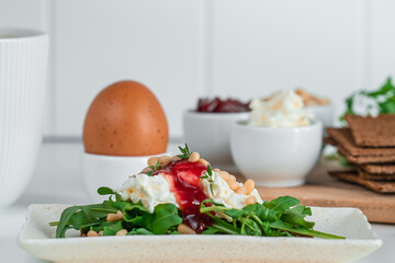 Close-up healthy breakfast with crispbread, egg, cream cheese, jam, arugula and pine nuts. Healthy breakfast concept.