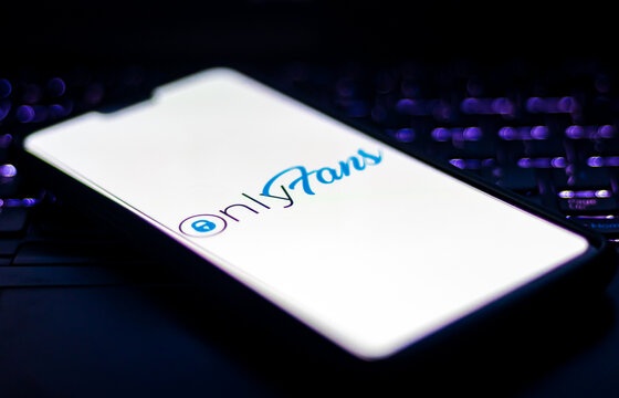 Onlyfans Logo On A Smartphone Against Laptop Keyboard With Bokeh In The Dark.
