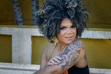 Beautiful happy African American woman enjoying life and having fun with hairstyle on city streets.