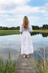 Frau im weißen Kleid blickt auf den See