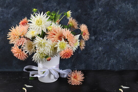 Bouquet of dahlias on a dark background in grunge style, Abstract floral arrangement, spring or autumn background with place for text, minimal holiday concept, low key still life, postcard.