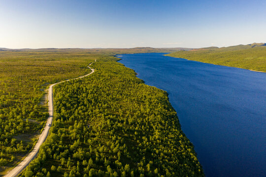 Aerial view of Pulmankijärvi lake and a road surrounded by forest in Nuorgam, Finnish Lapland