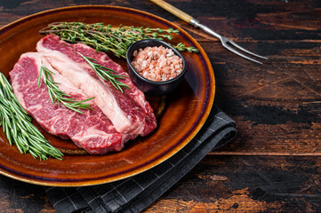 Fototapeta na wymiar Two sliced Raw Striploin steaks or New York steaks, beef meat. Dark wooden background. Top view. Copy space