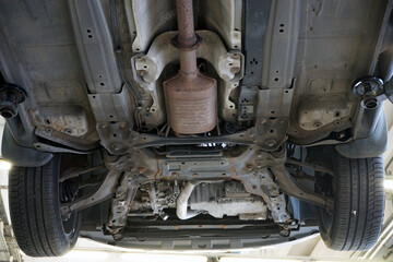 Bottom view of the front of a modern car. Suspension parts, exhaust system, catalytic converter. Selected focus.