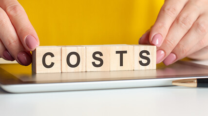 woman made word costs with wooden blocks, concept