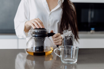 Woman brewing black tea in teapot at kitchen