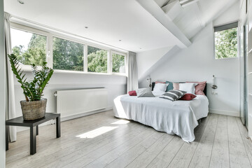 Modern bedroom in white colors with a large bed and windows