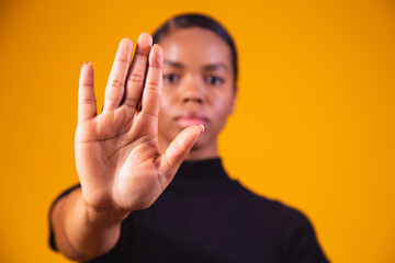 Young African American woman shown hand on sign for them to stop with racial prejudice.. - obrazy, fototapety, plakaty