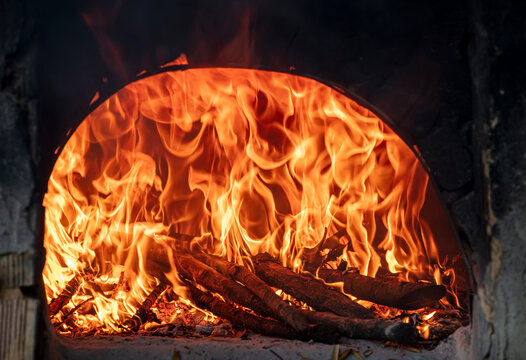 Image of a fiery and flaming brick oven. Firewood in the furnace.