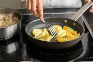 The hands of a man cook potatoes in a frying pan. Family dinner
