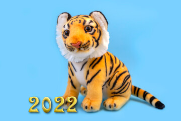 Toy tiger on the blue background. Symbol of the year 2022. Year of the tiger, golden inscription 2022