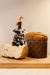 Panettone slice with Christmas tree
and blurry lights flashing in the background. Panettone concept. Christmas concept.