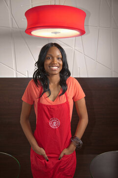 Portrait of Young African American female business owner standing underweight fixture wearing apron at bubble tea cafe 