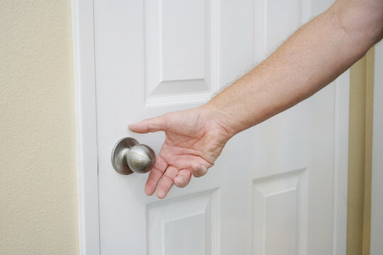 Man's hand reaching for a door knob.