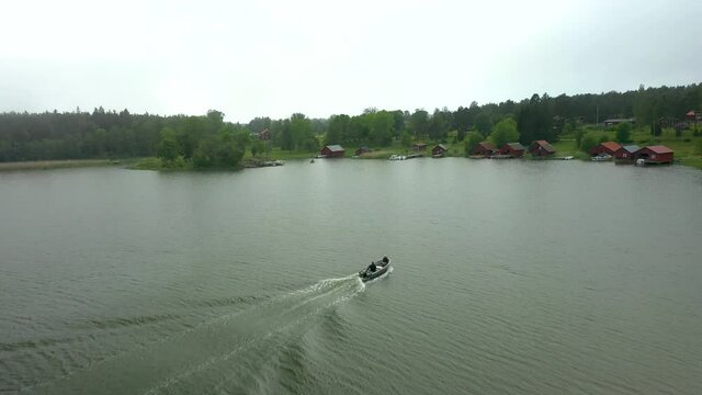 Aerial drone view flying over people in leisure boat, water and archipelago landscape