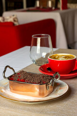 Plate of strawberry tiramisu on table with cup of coffee