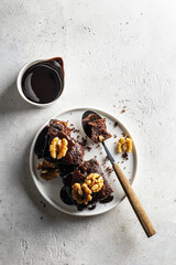 Chocolate Zucchini brownie on white plate on gray textured background