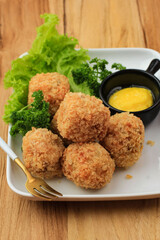 Delicious Homemade Brulee Bomb Made from Flour, Cheese, Milk Coated with Bread Crumb. Bitterballen Look a Like, Served on White Plate, Wooden Background with Parsley as Garnish