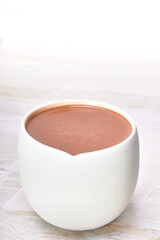 hot chocolate with vanilla in a white cup on a marble surface and white background with copy space for advertising.