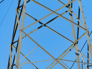 Fototapeta premium Close up of Powerline tower structure against clear sky in direct sunlight