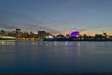 A skyline of Montreal Old Port and Downtown at the twilight blue hour. Foreground is Saint Lawrence (Laurent) river.