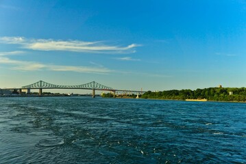 A skyline view a steel bridge across a river on bright sunny summer day. Jacques Cartier Bridge...