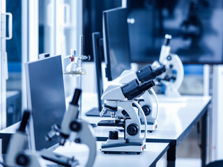 Close up shot of two eyes viewfinder scientific microscope in row of one eye microscopes line in blurred foreground on laboratory working table using for monitoring coronavirus covid 19 virus samples
