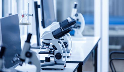 Close up shot of two eyes viewfinder scientific microscope in row of one eye microscopes line in blurred foreground on laboratory working table using for monitoring coronavirus covid 19 virus samples