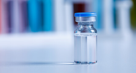 Close up shot of vaccine in small glass vial bottle with red label for protection prevention epidemic pandemic virus outbreak around world in laboratory blurred background