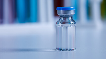 Close up shot of vaccine in small glass vial bottle with red label for protection prevention epidemic pandemic virus outbreak around world in laboratory blurred background