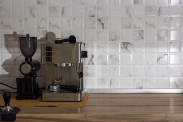 Espresso coffee machine and coffee bean grinder put on wooden table inside the kitchen with square...