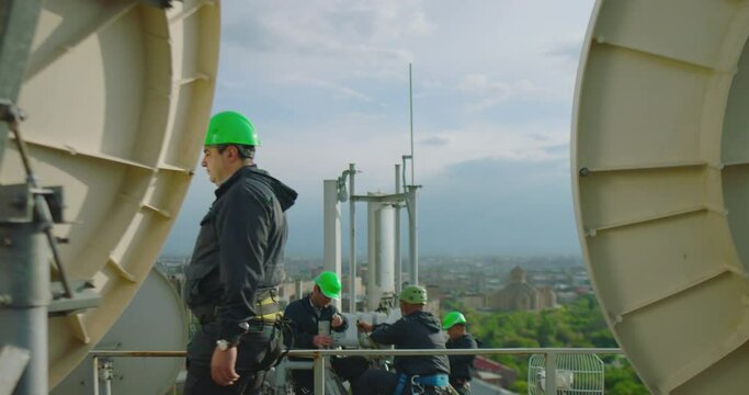 4k Workers servicing cellular antenna .  Engineer walking and following of work at telecommunications mast at height . Telecommunication technician working on top of cellular antenna. Cell tower .