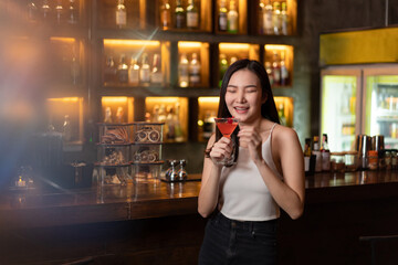 Nightlife concept a pretty girl with long hair wearing white and jeans holding a pink drink appreciating the musics alone in the bar