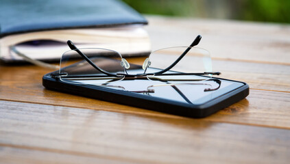 Rimless glasses, phone, notebook on the table close-up.