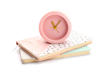 Alarm clock with notebooks on white background