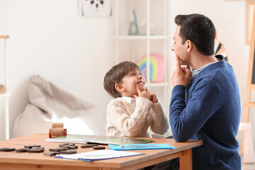 Speech therapist working with little boy in office