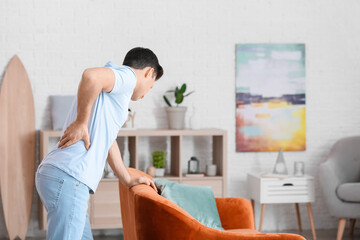 Young man suffering from back pain at home