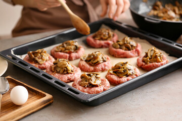 Woman putting mushrooms into minced meat boat at table