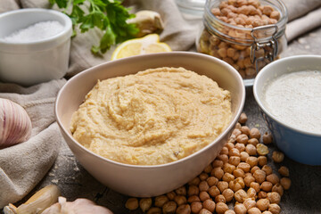 Bowl with tasty hummus and ingredients on table