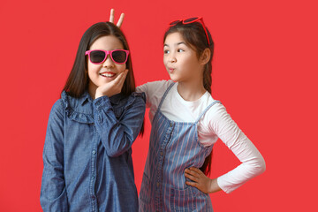 Funny little sisters on color background