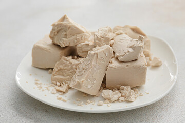 Plate with fresh yeast on light background
