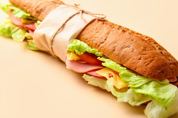 Bag with tasty ciabatta sandwich on color background, closeup